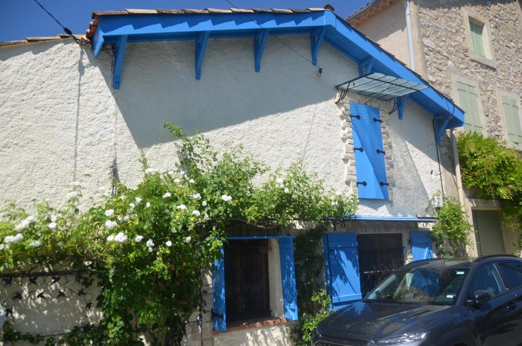 Causses-et-VeyranにあるLa Fontainebleuの青窓と木のある青い建物