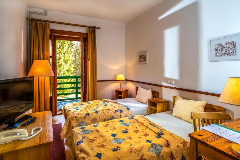 Pokój hotelowy z 2 łóżkami i biurkiem w obiekcie Bakony Hotel w mieście Bakonybél