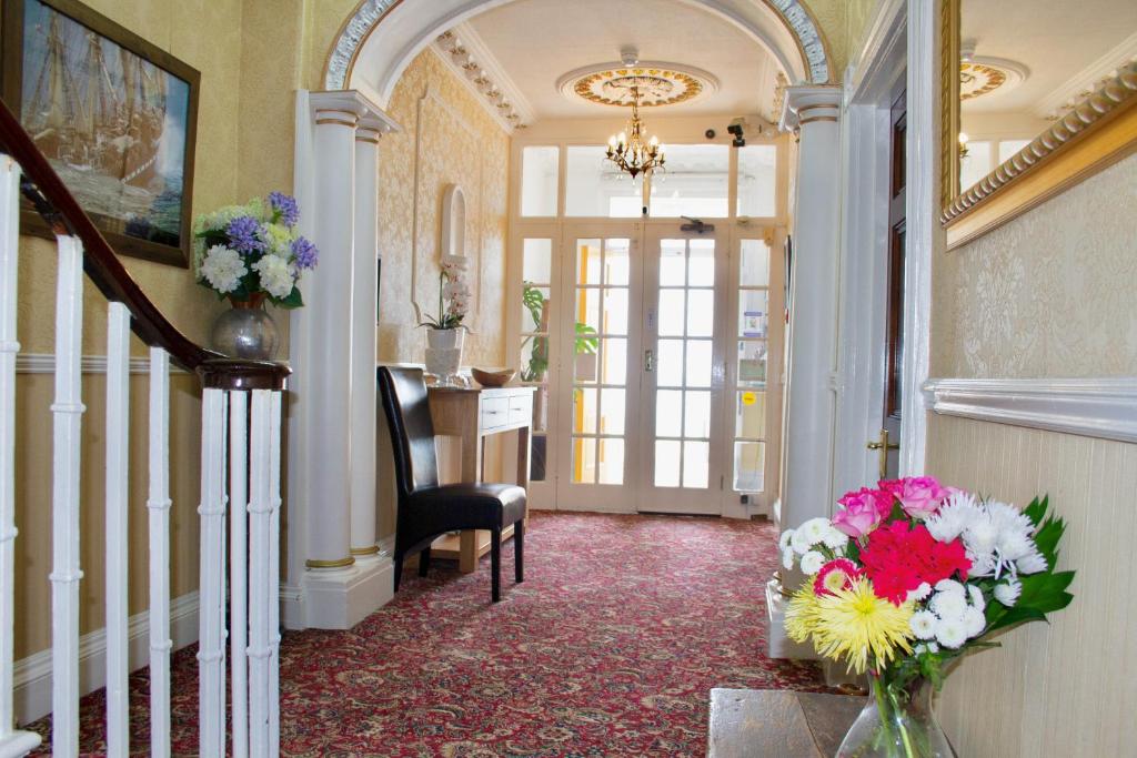 einen Flur mit einer Vase Blumen auf dem Tisch in der Unterkunft Helmsman Guesthouse in Aberystwyth