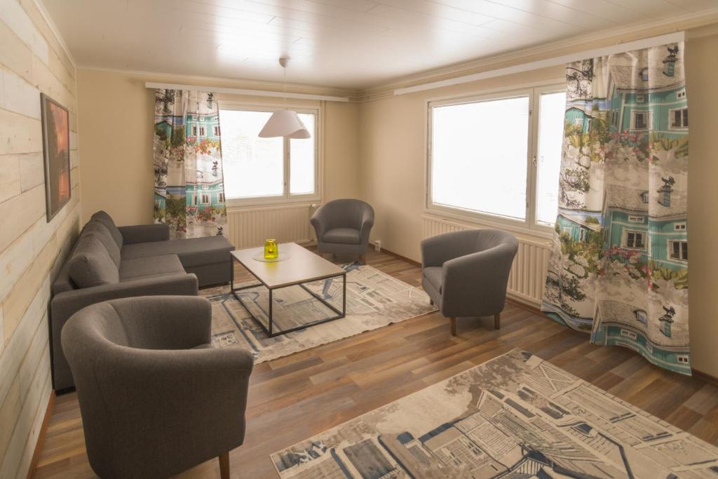 ein Wohnzimmer mit einem Sofa, Stühlen und einem Tisch in der Unterkunft Jääskän Loma Kojolapark, asunto 1, Alahärmä, Kauhava in Holma