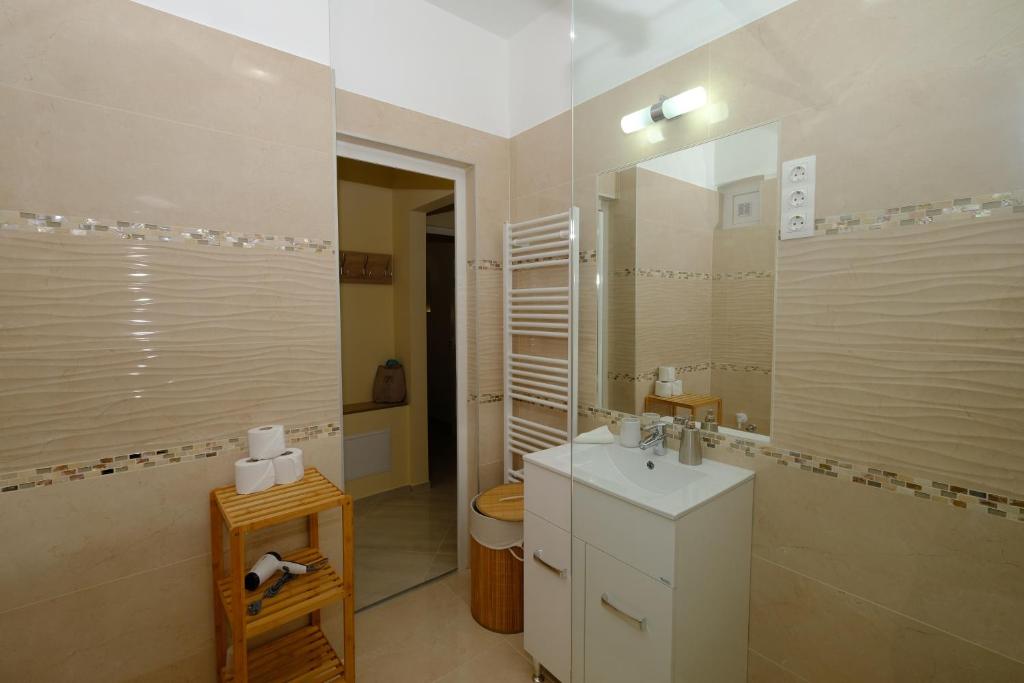łazienka z umywalką, toaletą i lustrem w obiekcie Mária Apartman Pécs w mieście Pecz