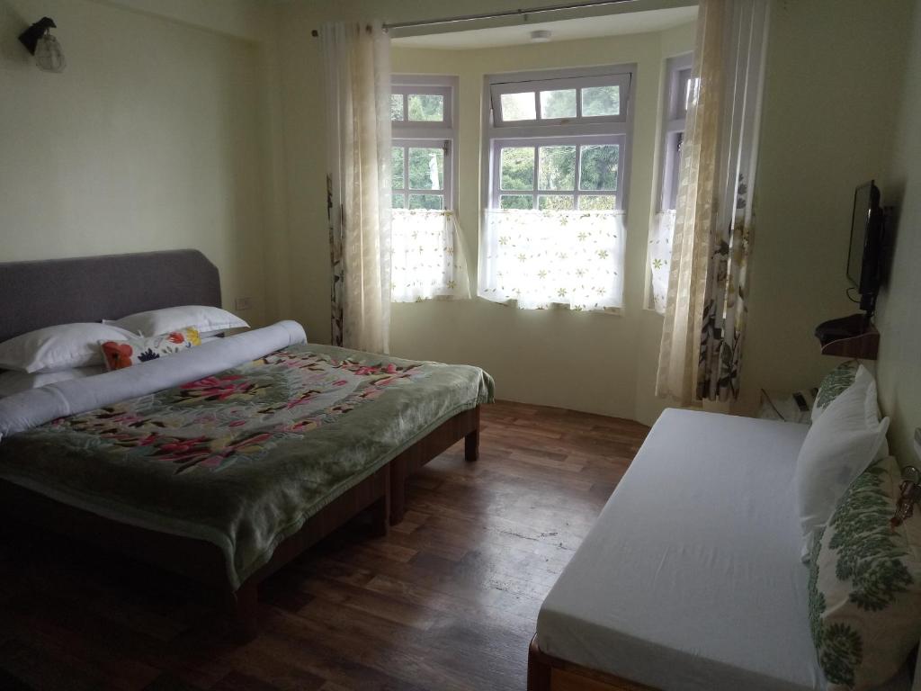 a bedroom with two beds and two windows at Green Tara Residency in Darjeeling