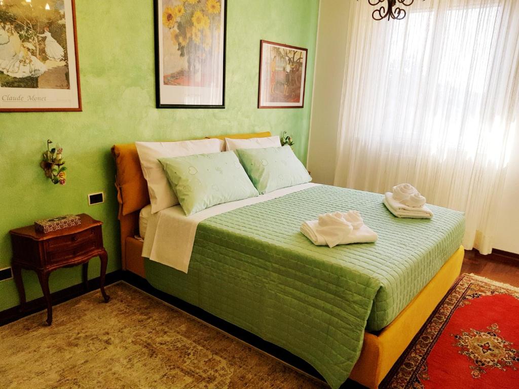 een groene slaapkamer met een bed met handdoeken erop bij Moncalvo in Relax in Moncalvo