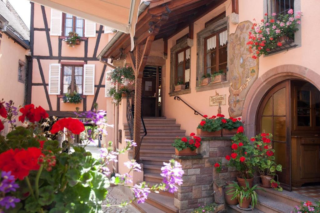 une vieille maison avec des fleurs devant elle dans l'établissement La Griffe à Foin au Restaurant raisin D'or, à Mittelbergheim