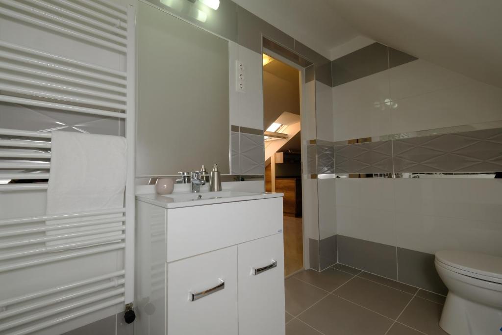 biała łazienka z umywalką i toaletą w obiekcie Mária Apartman Pécs w mieście Pecz
