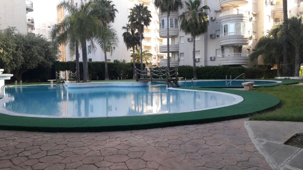 einen Pool in einem Park mit Palmen und Gebäuden in der Unterkunft Tropicana Park in Gandía