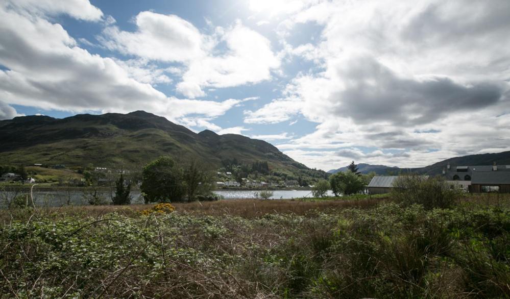 a view of a field with a lake and mountains at The Sheiling in Dornie