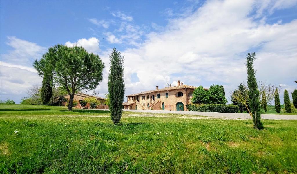 a large house in the middle of a field with trees at Agriturismo Casa Rossa in Chianciano Terme