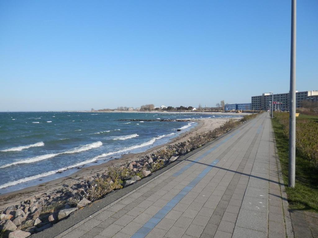 a sidewalk next to a beach with rocks and the ocean at Ostseeblick Heiligenhafen in Heiligenhafen