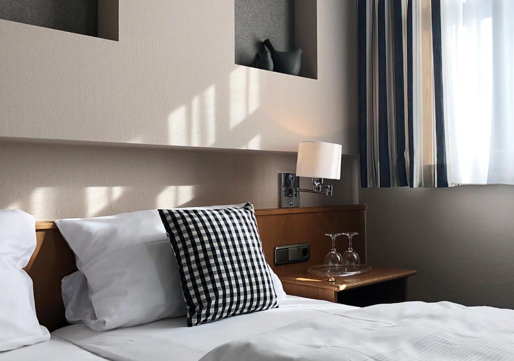 施韋因福特的住宿－Mangolds Boutique Hotel & Fruehstuecksmeisterei，一间卧室配有一张带白色床单的床和一扇窗户。
