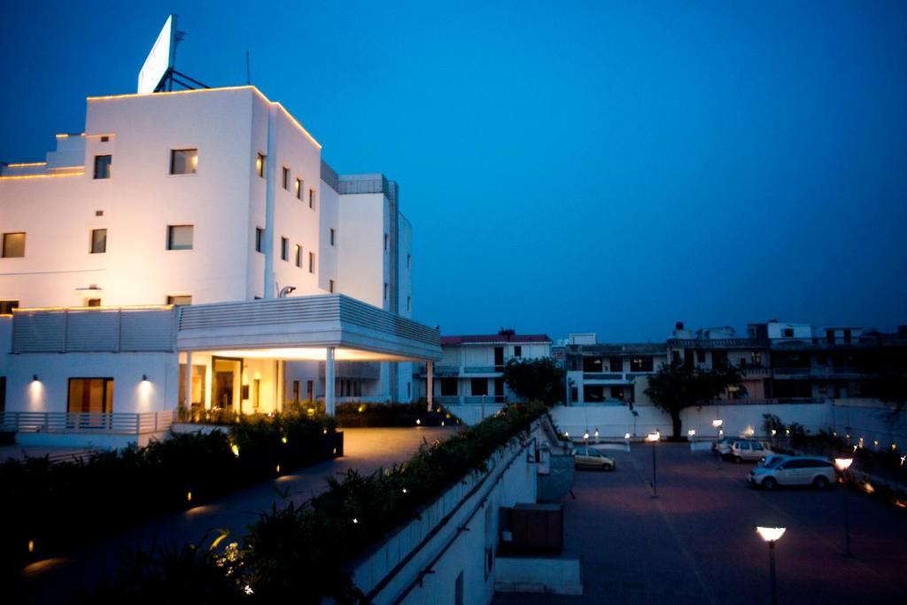 a large white building with a parking lot at night at Vibe By The LaLiT Traveller in Faridabad