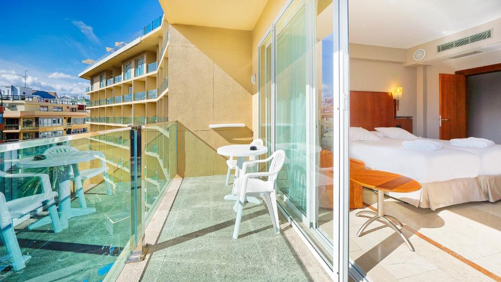 a room with a balcony with a bed and a table at Bull Reina Isabel & SPA in Las Palmas de Gran Canaria