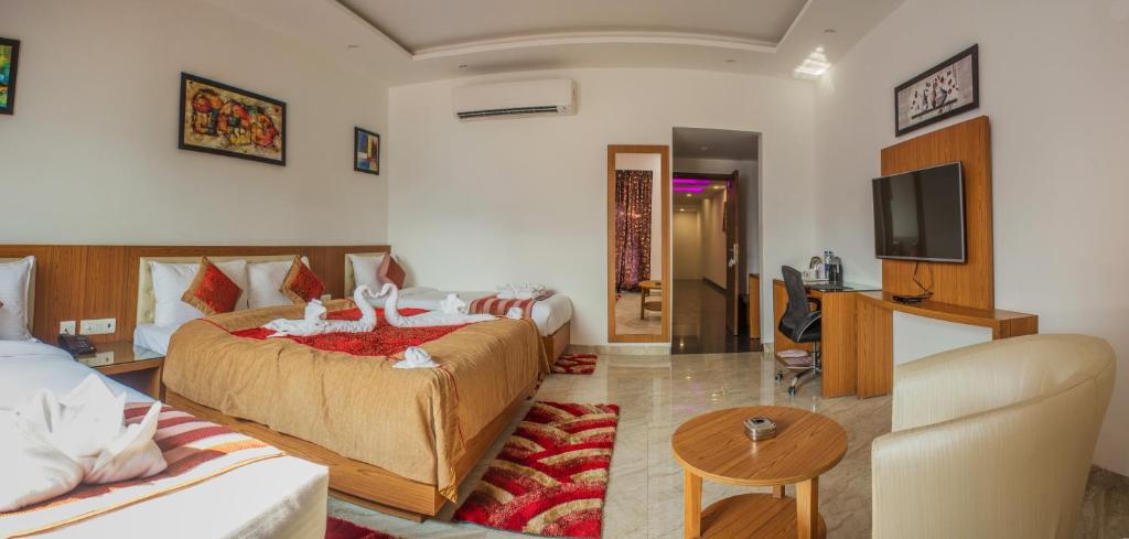 una camera d'albergo con due letti e una televisione di Hotel Suktara International a Siliguri