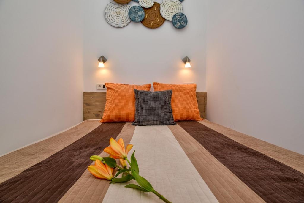 ein Bett mit orangefarbenen Kissen und Blumen darauf in der Unterkunft Heart Apartment with FREE Private Parking in Budapest