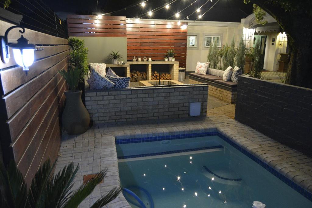 a swimming pool in a backyard at night with lights at Grey Manor Guesthouse in Potchefstroom