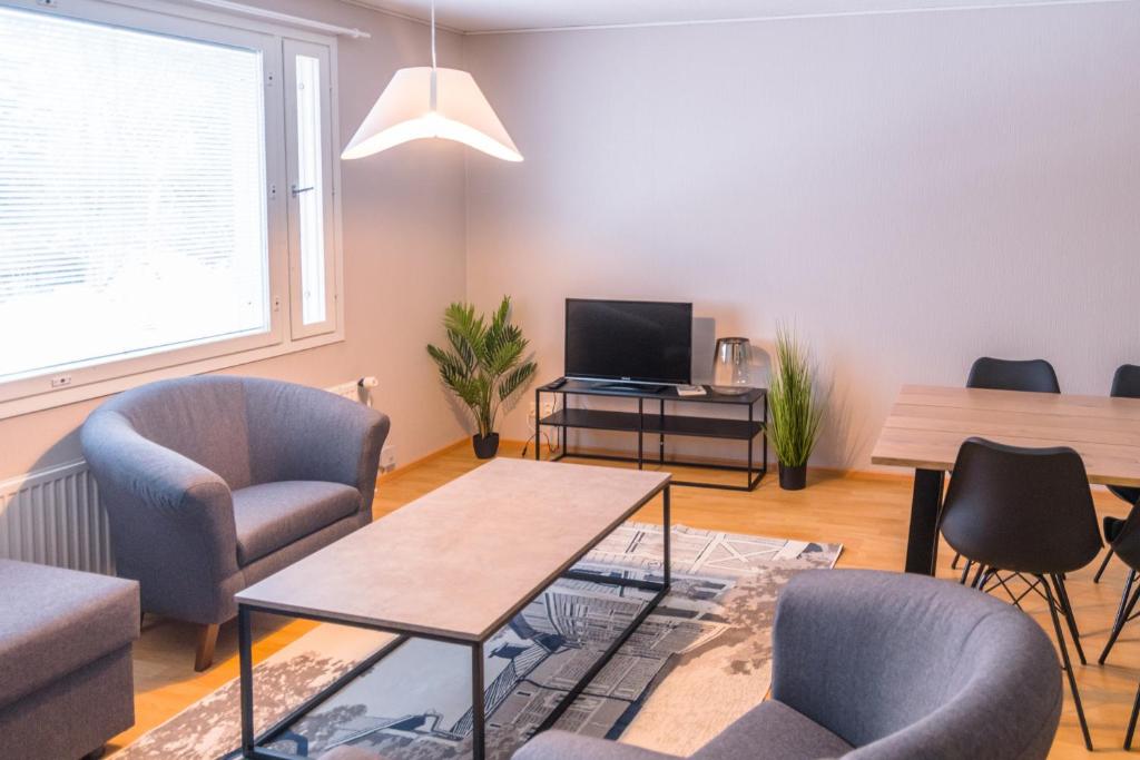 sala de estar con sillas, mesa y TV en Jääskän Loma Ratatie 3 asunto 6 Kauhava en Kauhava