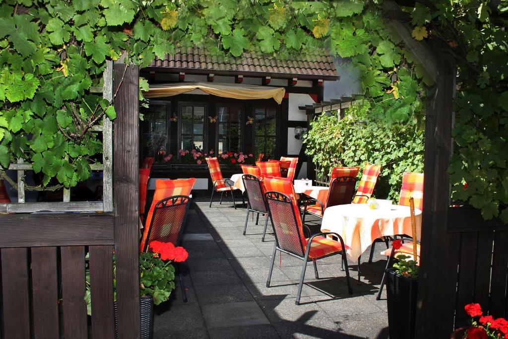 un patio al aire libre con mesas, sillas y vides en Hotel Cordial en Lennestadt