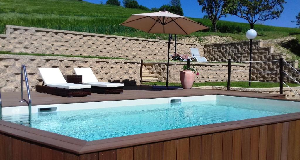 basen z 2 krzesłami i parasolem w obiekcie Bed And Breakfast Olimpia w mieście San Salvatore Monferrato