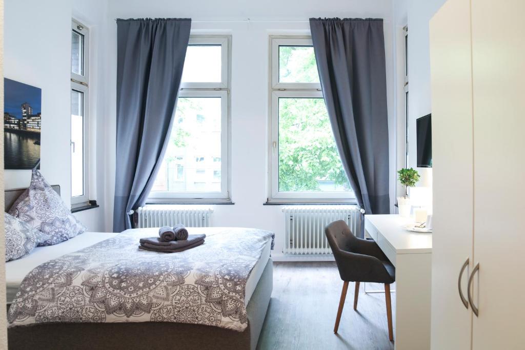 a bedroom with a bed and a desk and two windows at dreams Düsseldorf in Düsseldorf