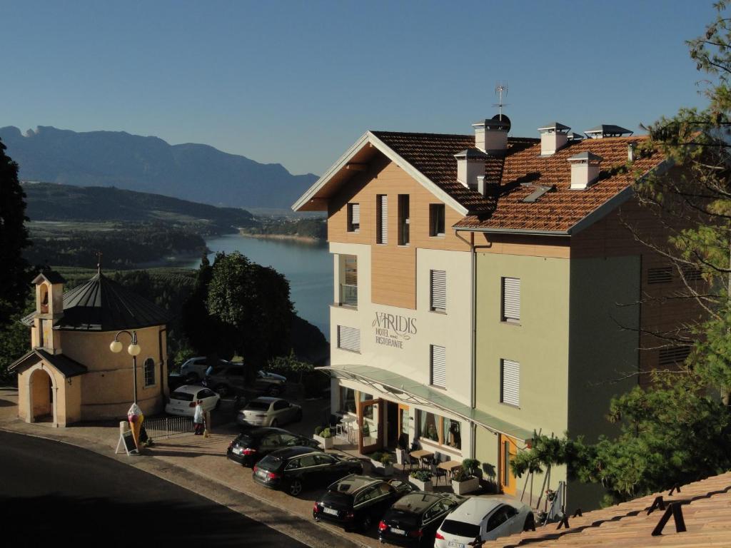 un gran edificio con coches estacionados en un estacionamiento en Viridis Hotel, en Revò