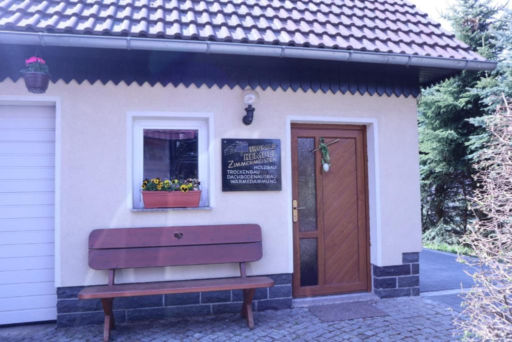 un banc devant un bâtiment avec une porte dans l'établissement Die gemütliche Ferienwohnung für jedermann!, à Oppach