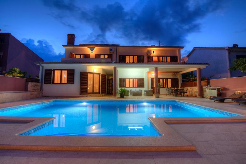 a house with a swimming pool in front of a house at Villa Komel with Pool in Fažana