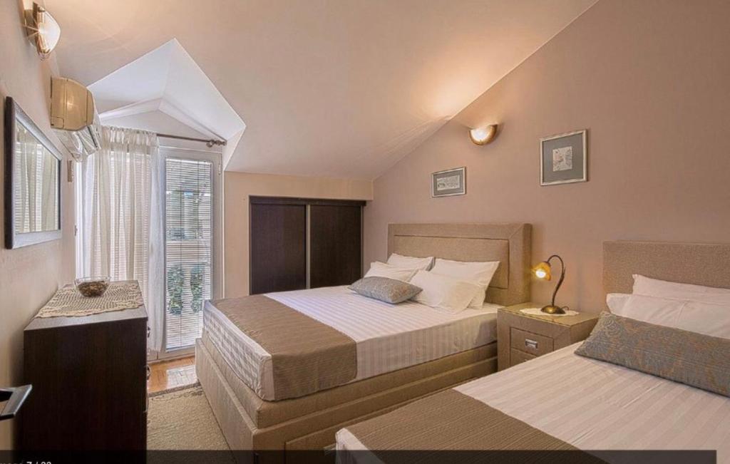 um quarto com 2 camas e uma janela em Apartmani Asanović em Budva