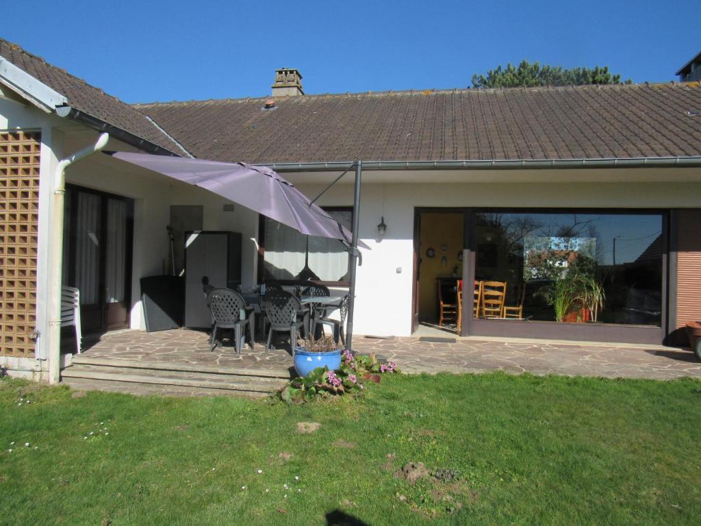 een huis met een patio met een parasol bij La Hugotière in Friville-Escarbotin
