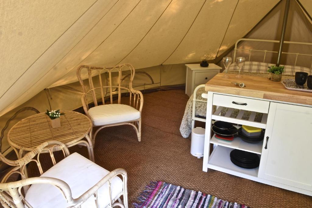 a tent with chairs and a table in a room at Glamping at Camping La Source in Saint-Pierre-dʼArgençon