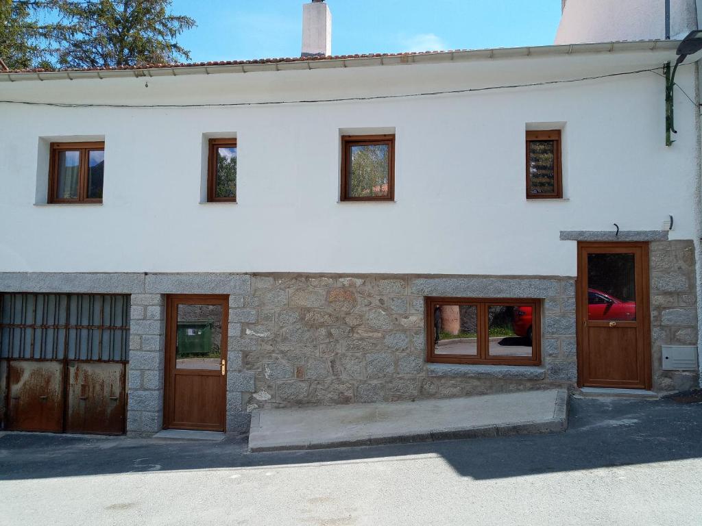 een wit huis met houten deuren en ramen bij La Parra de Pepa in Cercedilla