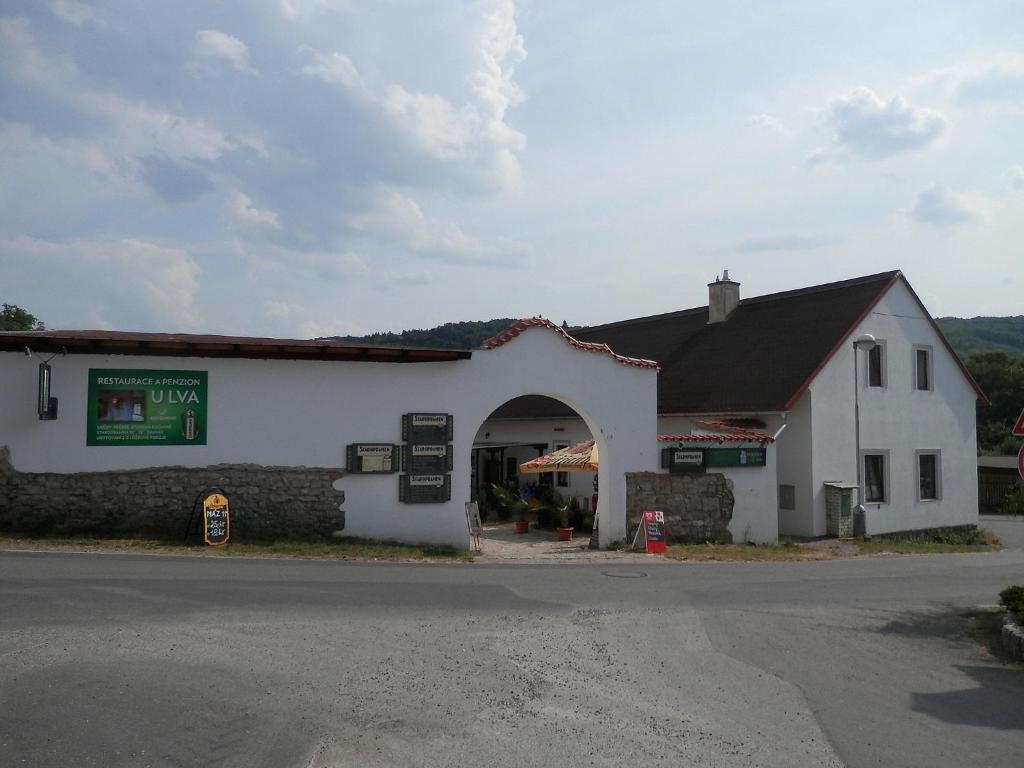 a white building with an archway next to a street at Restaurace a penzion U Lva in Karlštejn