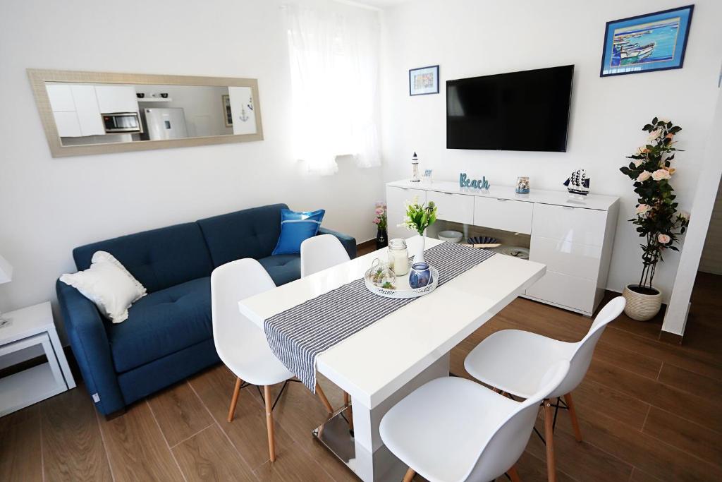 a living room with a blue couch and a table and chairs at Apartments Romarin in Supetar