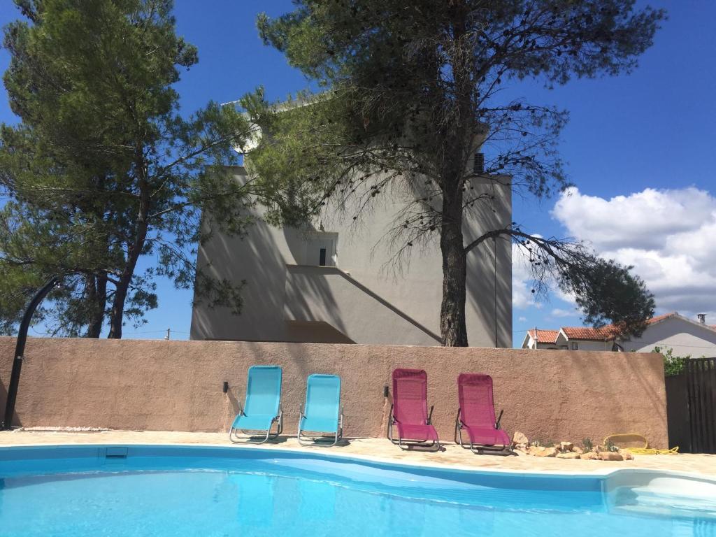 Apartments Vila Moli في بيبينيا: وجود ثلاثة كراسي للجلوس بجانب المسبح