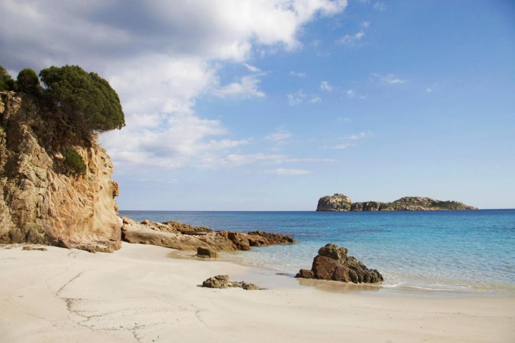 una spiaggia sabbiosa con rocce e oceano di Casa Vacanze Nonna Defenza a Teulada
