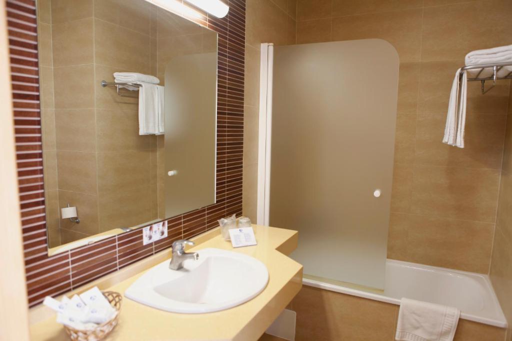 a bathroom with a sink and a mirror and a tub at Hotel Adiafa in Barbate