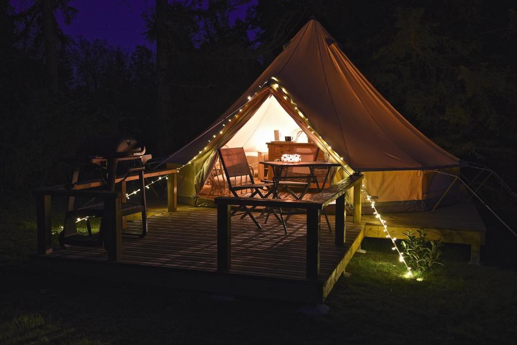 a tent with a table and chairs and lights at Glamping at Camping La Source in Saint-Pierre-dʼArgençon