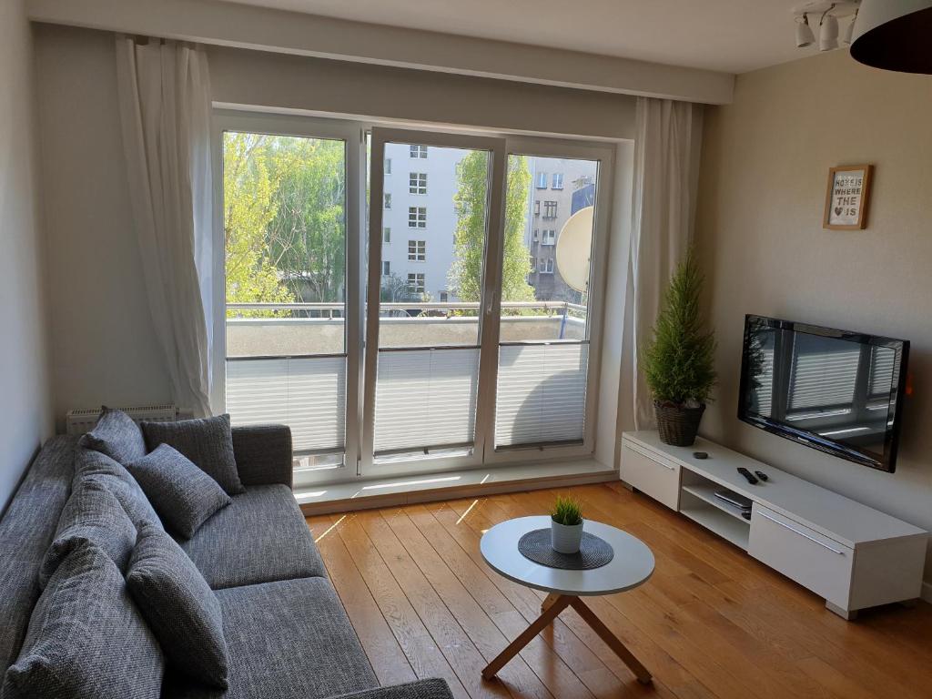 ein Wohnzimmer mit einem Sofa und einem TV in der Unterkunft Apartament Starowiejska in Gdynia