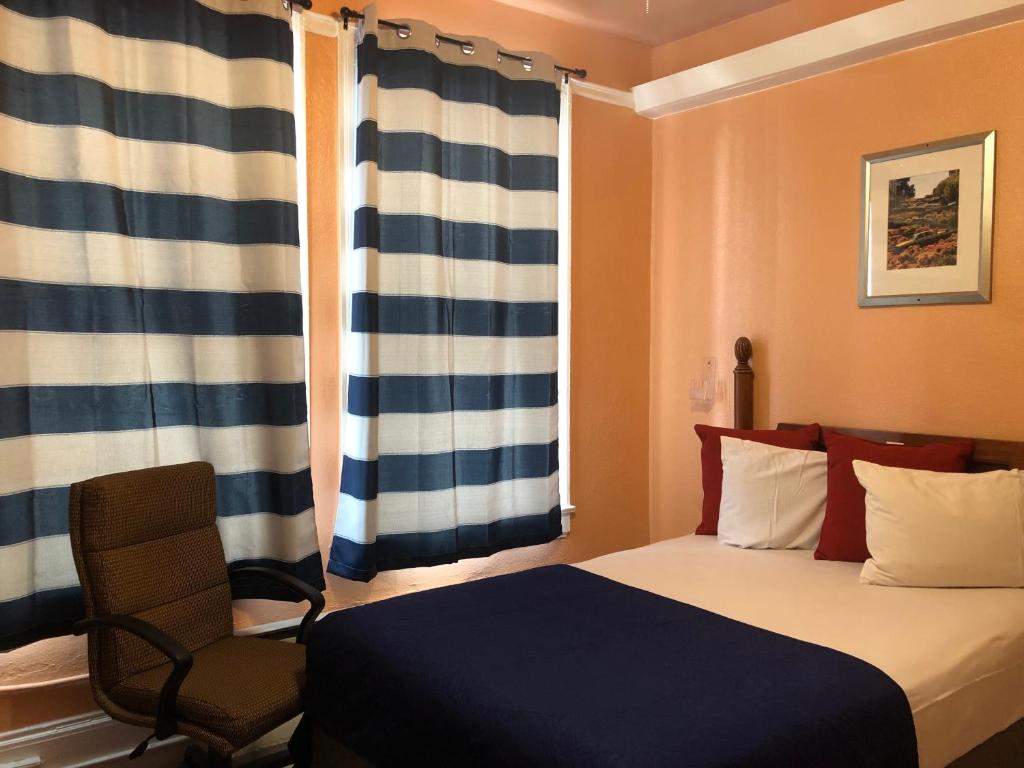 a bedroom with a bed and a chair and a window at Haveli Hotel - Downtown Market San Francisco in San Francisco