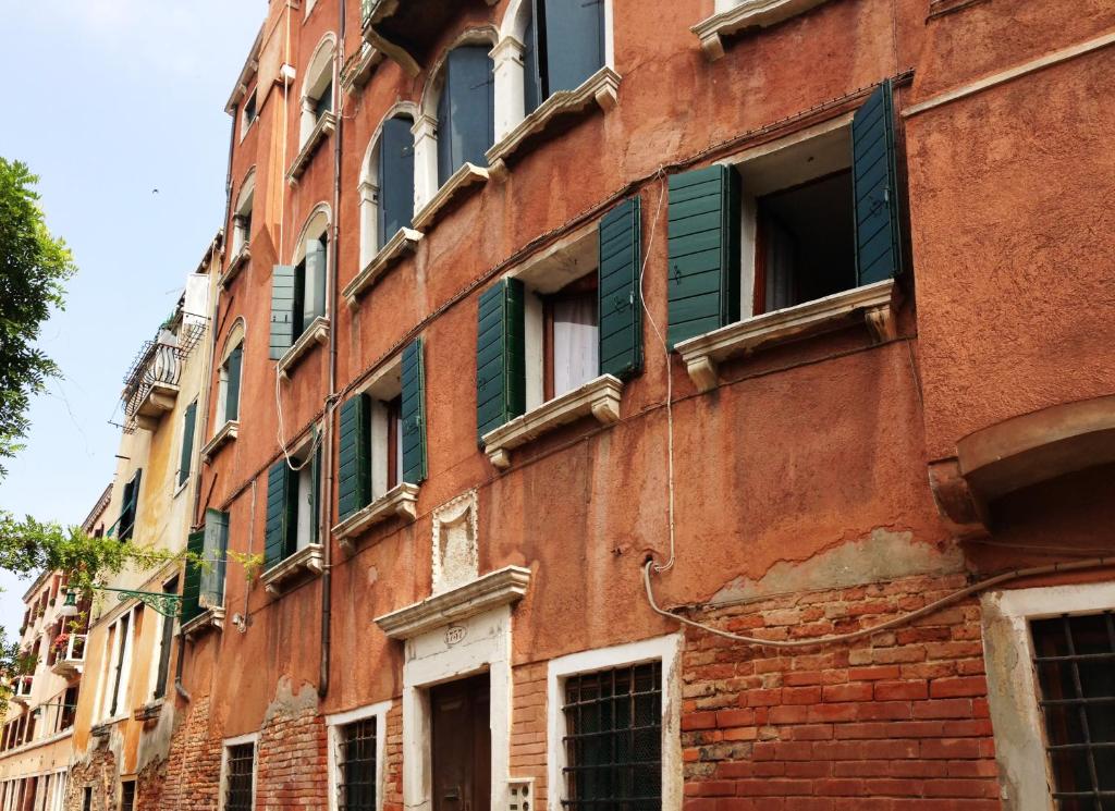 ein altes rotes Backsteingebäude mit grünen Rollläden in der Unterkunft Sweet Home New in Venedig