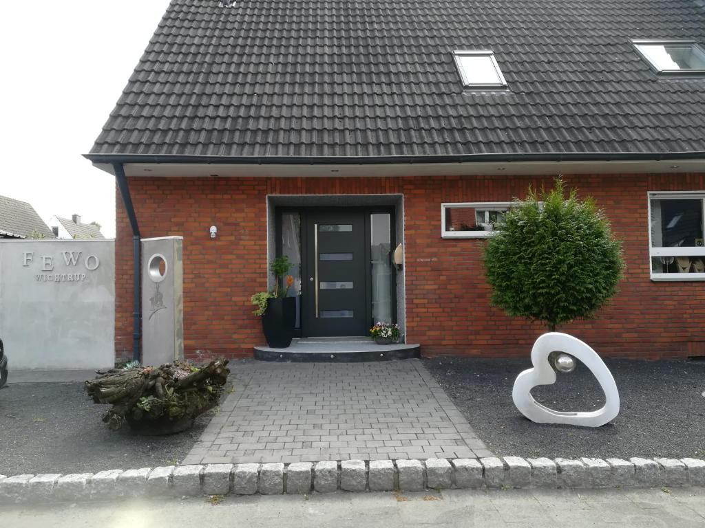 uma casa de tijolos vermelhos com uma porta preta e uma estátua de cisne branco em Fewo Wichtrup em Emsdetten