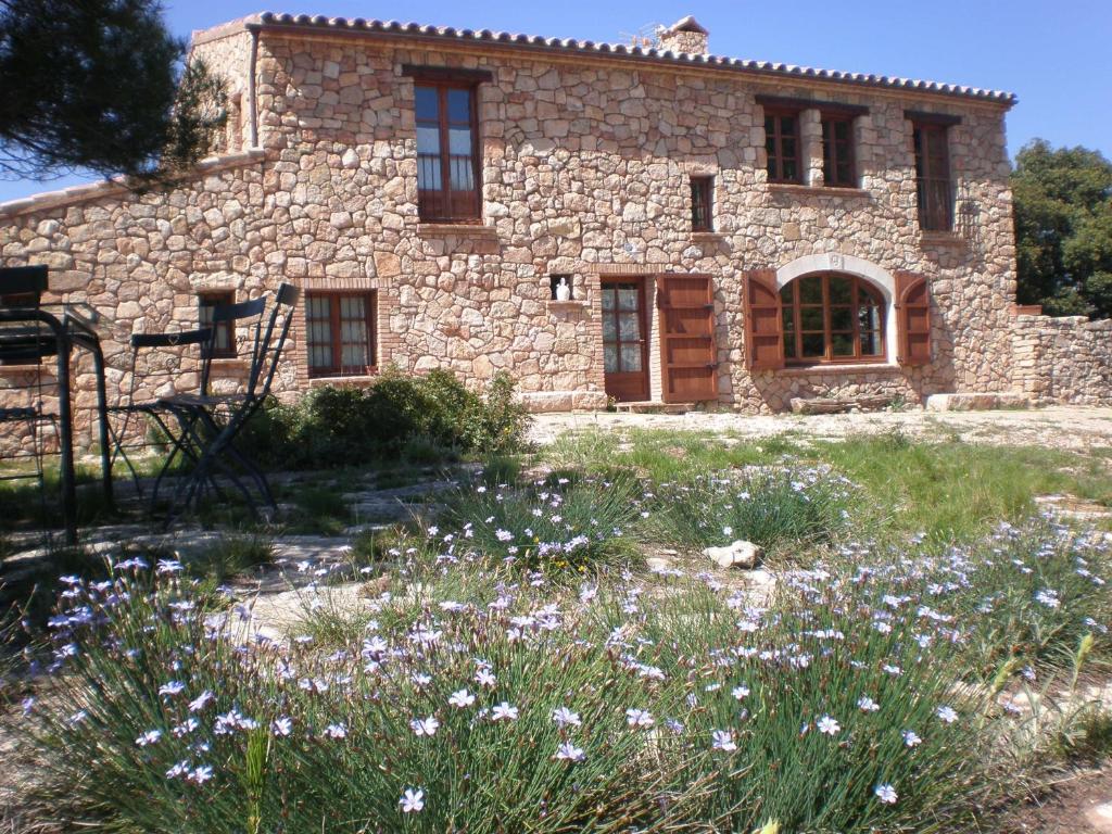 una vieja casa de piedra con flores delante en Mas del Salin, en Cornudella