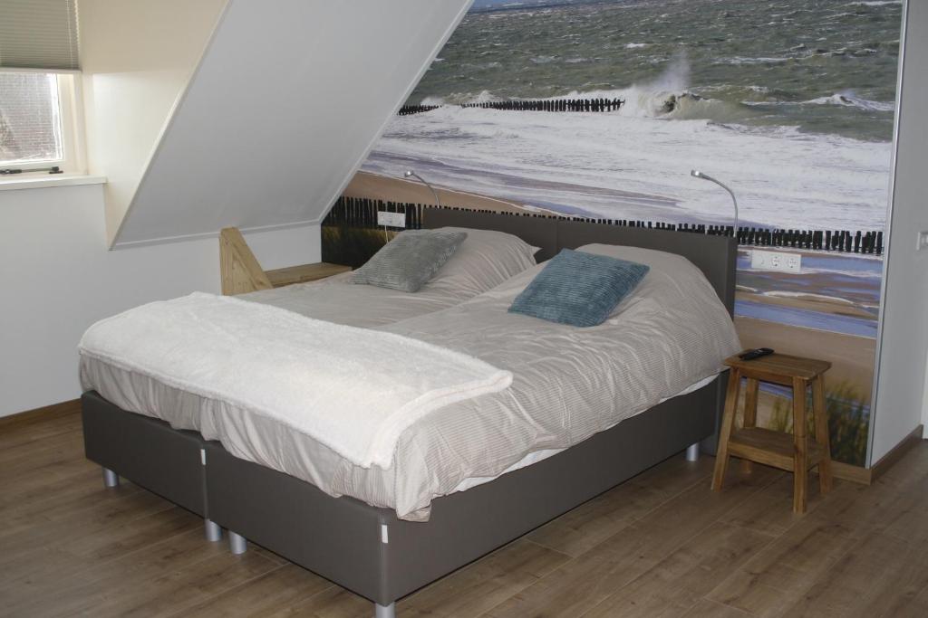 a bed in a bedroom with a picture of the ocean at Hiltop in Domburg