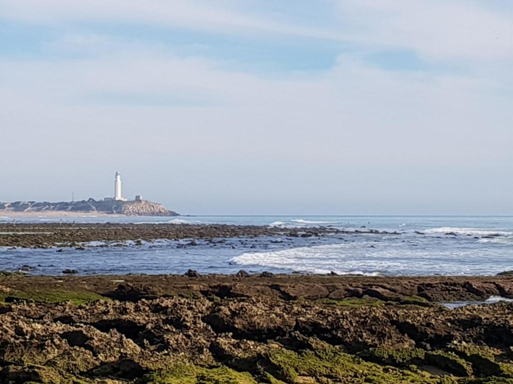 a beach with a lighthouse in the distance at Residencial La Teja in Zahora