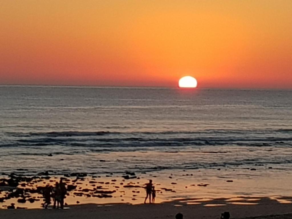 a group of people standing on the beach at sunset at Residencial La Teja in Zahora