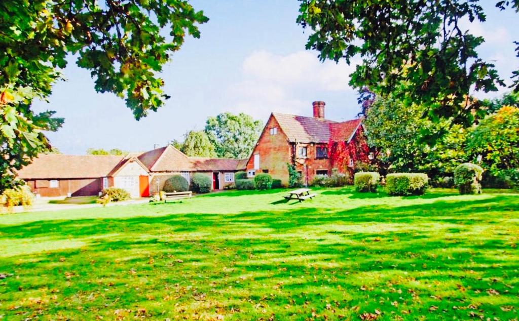a large red house with a green yard at Oldlands Farmhouse Gatwick in Horley