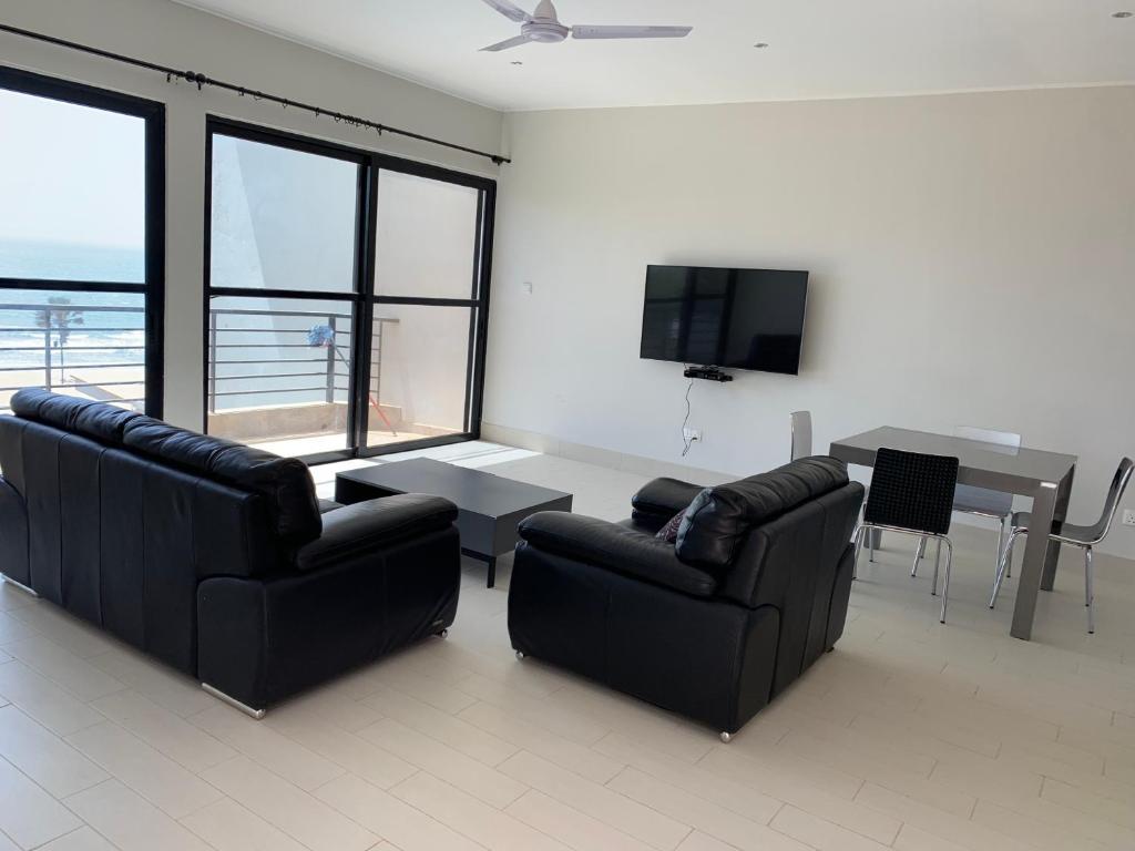 sala de estar con 2 sofás, mesa y TV en WATERFRONT FLAT en Sere Kunda NDing