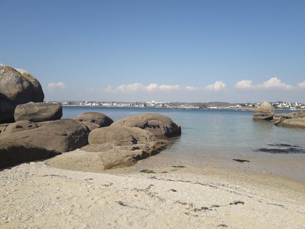 une plage avec des rochers dans l'eau et une ville dans l'établissement Park Rouz Beach, à Concarneau