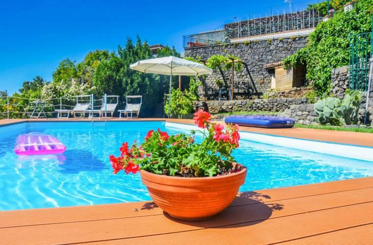 a pot of flowers sitting on a table next to a swimming pool at Villa 'Nduccia in Pedara