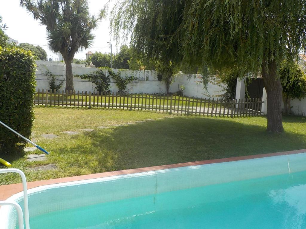 a swimming pool with a tree and a fence at Okira beach house in Aguda