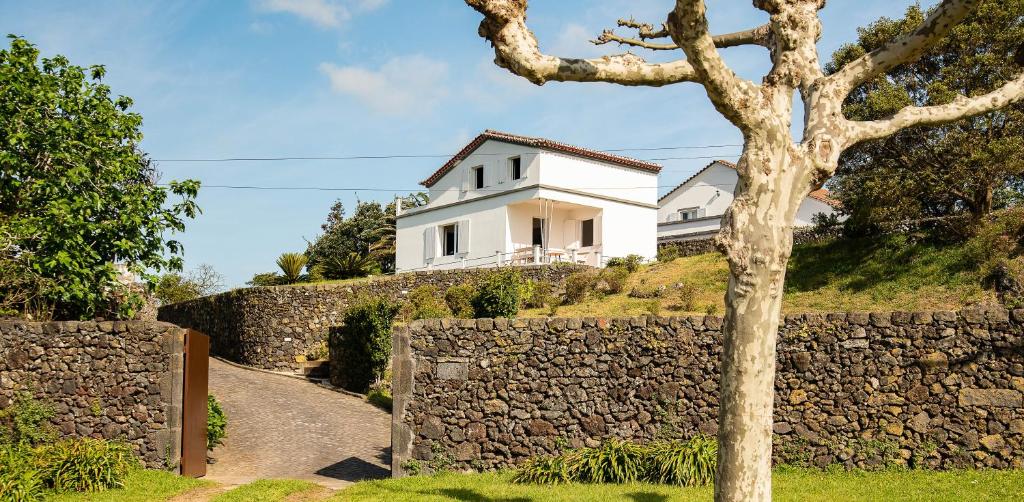 a white house on a hill with a stone wall at Pedreira da Guia in Lagoa